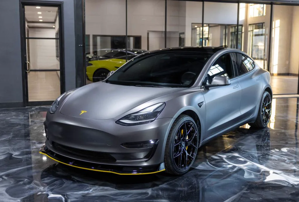 Satin grey Tesla Model 3 with dark window tint in the Apex showroom